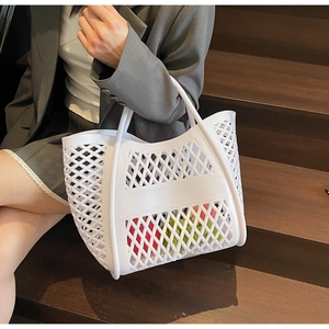 Vue détaillée d'un sac cabas ajouré blanc tenu par un mannequin sur des escaliers