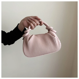 Detail of light pink pleated handbag featuring intricate accordion folds and knotted handle