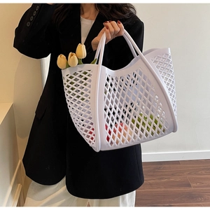 Détail du sac cabas blanc ajouré tressé rempli de fleurs fraîches et de fruits