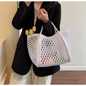 Panier tressé blanc ajouré tenu à la main avec une tulipe et des articles de loisirs