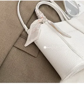 Detail of white lychee leather tote bag with printed silk scarf on brown blazer background