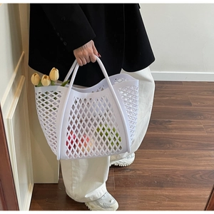 Gros plan d'un sac cabas en maille blanche rempli de fleurs et de fruits dans un décor intérieur