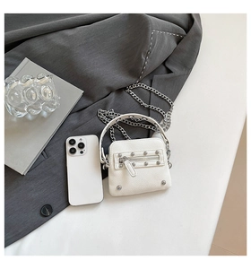 Detail of white studded mini bag with silver chain strap and lychee texture finish