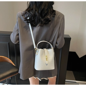 Detailed back view of a white crocodile-embossed bucket bag with gold metal clasp