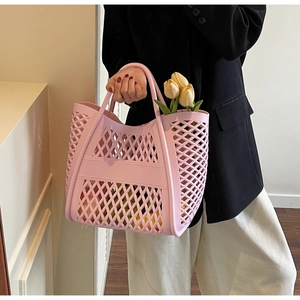 Gros plan du sac cabas ajouré rose avec motifs géométriques et poignées rondes élégantes