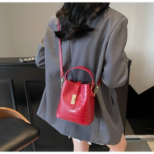 Detail view of red crocodile embossed bucket bag with gold metal buckle and strap