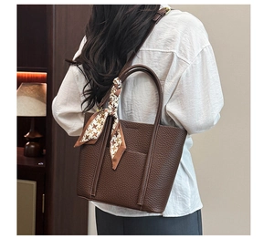 Detail of dark brown tote bag with pebble leather texture and houndstooth scarf