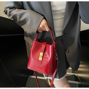 Close-up of red crocodile pattern bucket bag with golden twist lock detail
