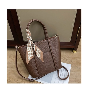 Detailed shot of dark brown pebbled leather tote bag with silk scarf and gold hardware