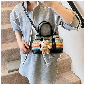 Detail of colorful woven tote with bear charm on model in a modern indoor setting