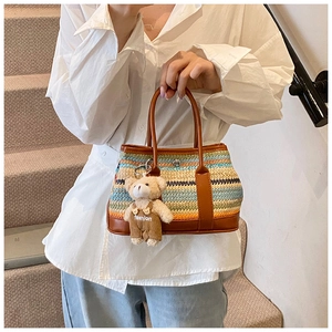 Detail of colorful striped woven bag with brown leather trim and cute bear charm