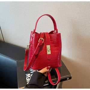 Detail of red croc-embossed bucket bag showing the golden twist lock and leather texture