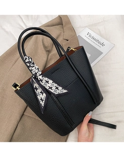 Detail of black pebbled leather tote bag with houndstooth scarf on a blazer background