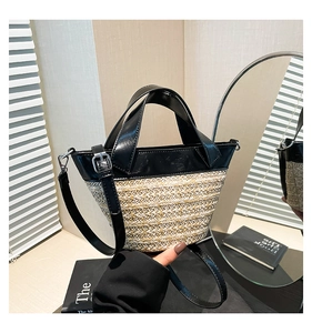 Detail of woven straw and black leather bucket bag with silver buckles and strap