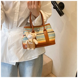 Detail of multi-color woven straw bucket bag with leather trim and bear charm