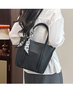 Detail of black lychee grain leather tote bag with geometric silk scarf on handle