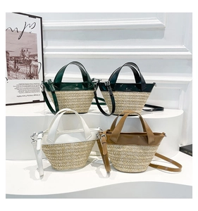Detail of woven straw tote bags with faux leather trim in green, black, white, and brown