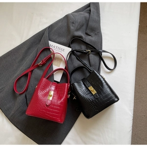Detailed close-up of red and black crocodile pattern bucket bags with gold metal clasps