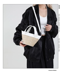 Detail of white leather and straw woven bucket bag carried by model in black blazer