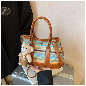 Detail of colorful woven shoulder bag with brown leather strap and teddy bear charm