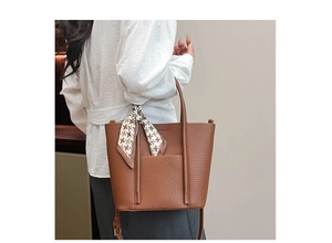 Detail of brown litchi leather tote bag with stylish silk scarf and cylindrical handle
