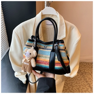 Detail of colorful striped woven shoulder bag with cute bear charm and black leather straps