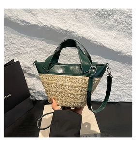Detail of hand-held woven bucket bag with cream straw and dark green leather panels