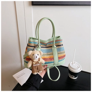 Detail of colorful striped woven handbag with green leather handle and cute bear charm