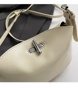 Detail of cream leather crossbody bag featuring a silver turn-lock and soft texture