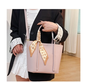 Close-up of pink litchi grain leather tote bag with elegant houndstooth scarf on handle