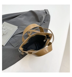 Detailed top view of khaki woven bucket bag with zipper closure and black fabric lining