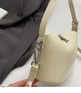 Detailed macro view of silver metal buckles and fine stitching on the cream leather bag