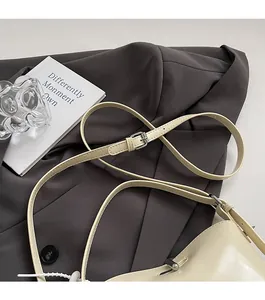 Detail of adjustable slender strap with silver buckle on a beige leather bag
