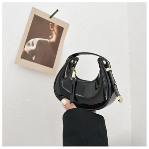Detailed view of mini crescent moon bag in black patent leather with gold hardware