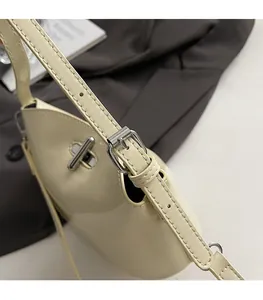 Detail of adjustable shoulder strap with silver buckle on cream faux leather bag