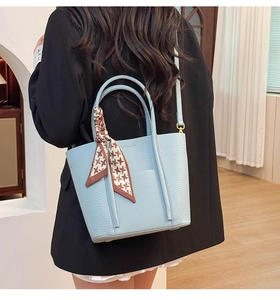 Detail of light blue pebble leather tote bag with a houndstooth scarf on the handle