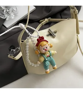 Detail of cream white shoulder bag with silver twist lock and cute pearl doll pendant