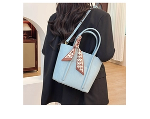 Detailed view of light blue leather tote bag with a checkered silk scarf on the handle