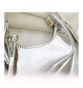 Detail of silver metallic crescent bag showing rivets and precise stitching on faux leather