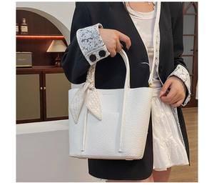 Detail of white litchi pattern leather tote bag with geometric silk ribbon decoration