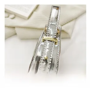 Detailed side view of silver crescent bag featuring gold hardware and precise stitching
