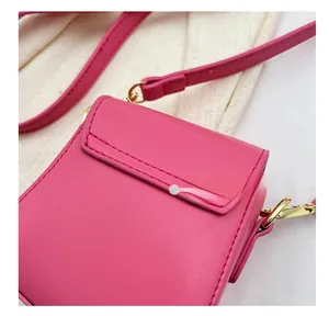 Gros plan sur le mini sac rose vif montrant les coutures et détails dorés