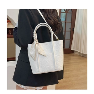 Close-up of white lychee leather tote bag with a beige plaid scarf on the handle