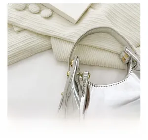 Detail view of smooth silver zipper and mirror finish texture on mini crescent handbag