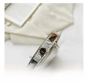 Detail of silver mirror crescent bag handle with reinforced stitching and gold hardware