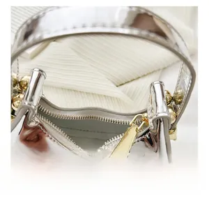 Macro detail of silver mirror moon bag showing golden hardware and textile lining