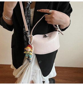 Detail of pink patent leather handbag with pearl charm worn over a black blazer