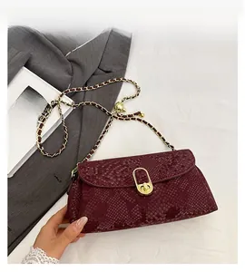 Detail of burgundy snakeskin texture bag with gold chain and oval twist lock clasp