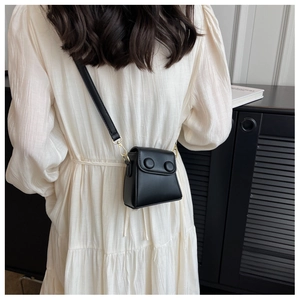Détail d'un mini sac bandoulière noir avec boutons décoratifs ronds et boucles dorées