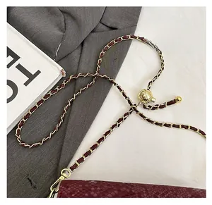 Detail of red snake-pattern bag with gold chain strap and adjustable metal ball buckle